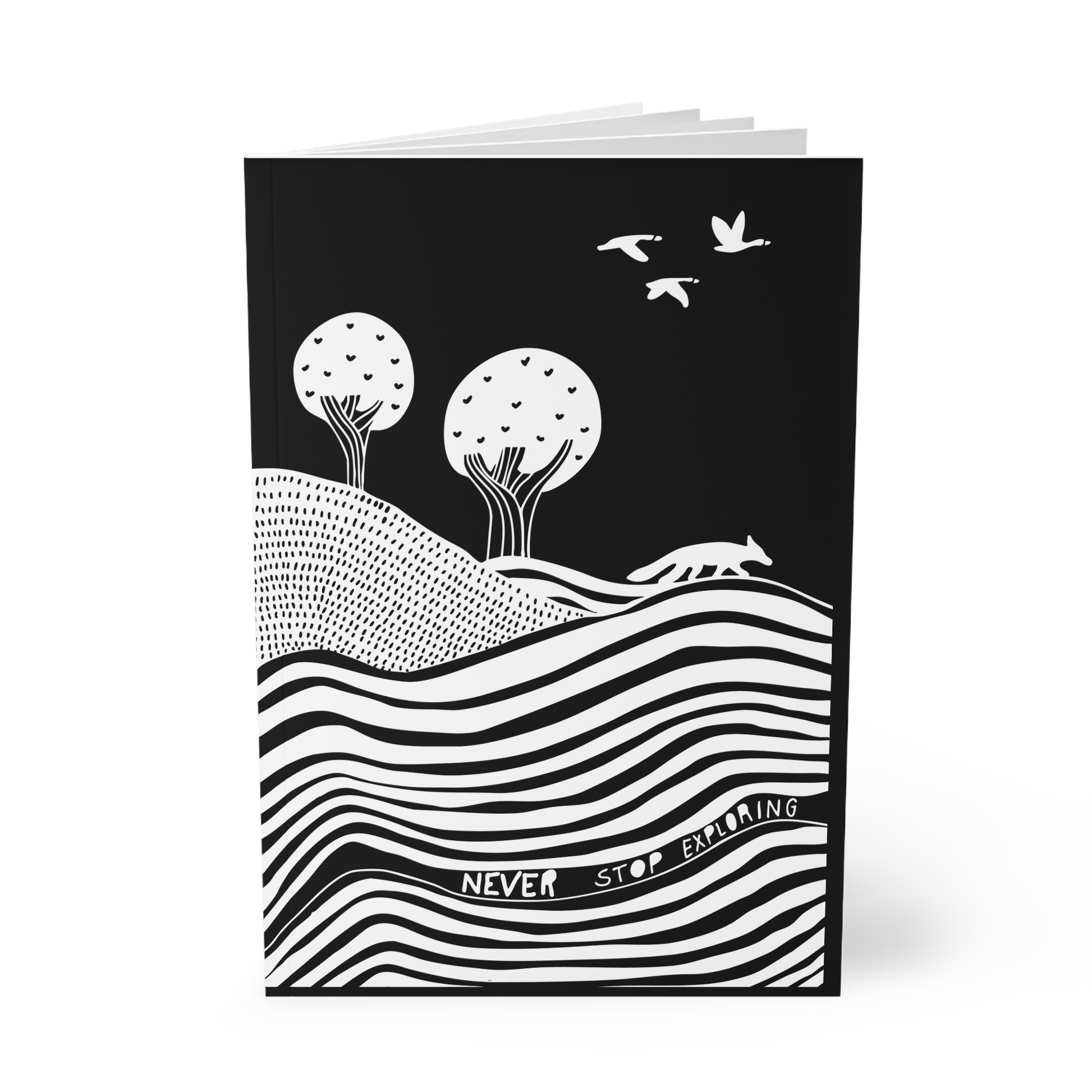 Black notebook with white landscape illustration and text 'Never Stop Exploring'.